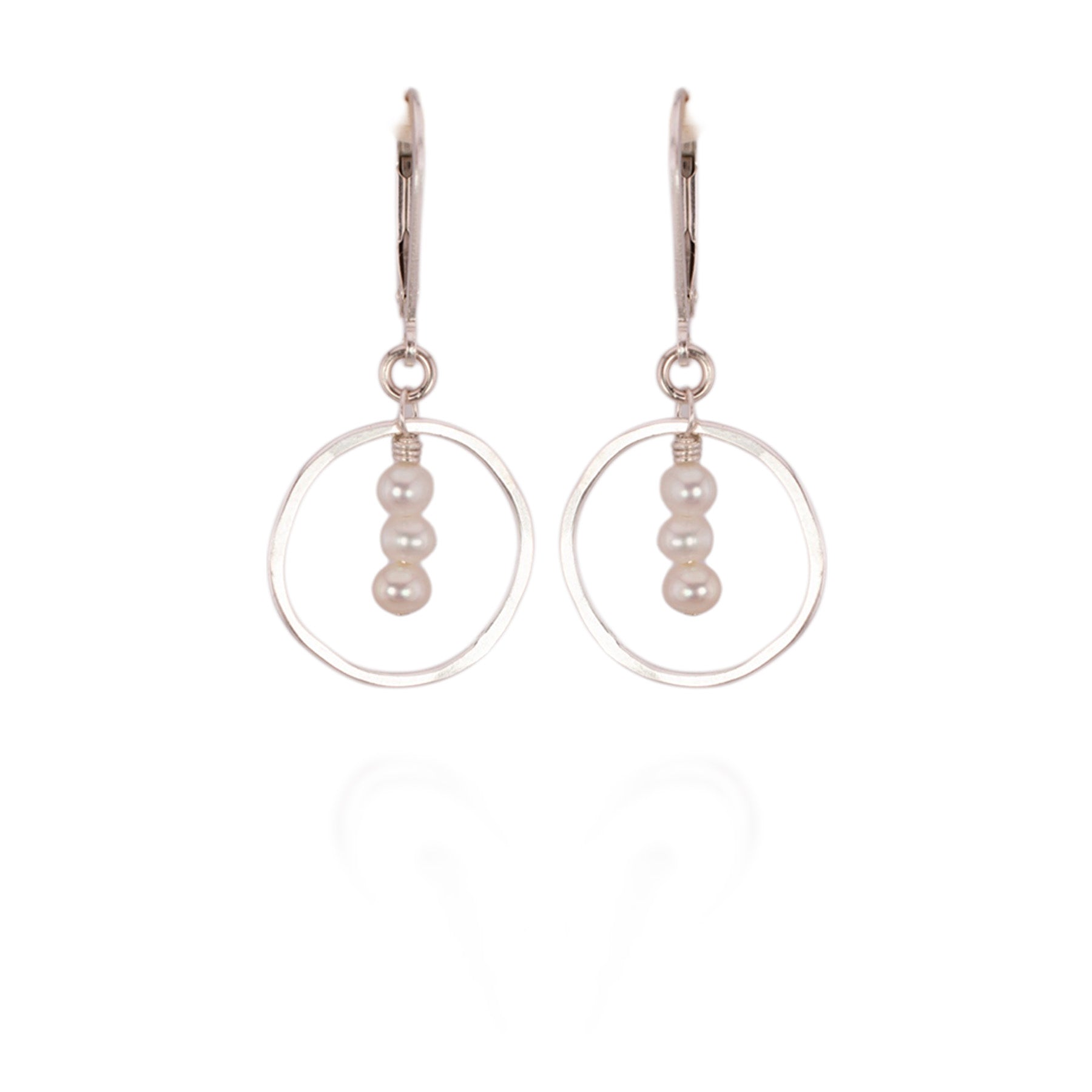 Pair of earrings with circular clear frames and pearl beads on a white background
