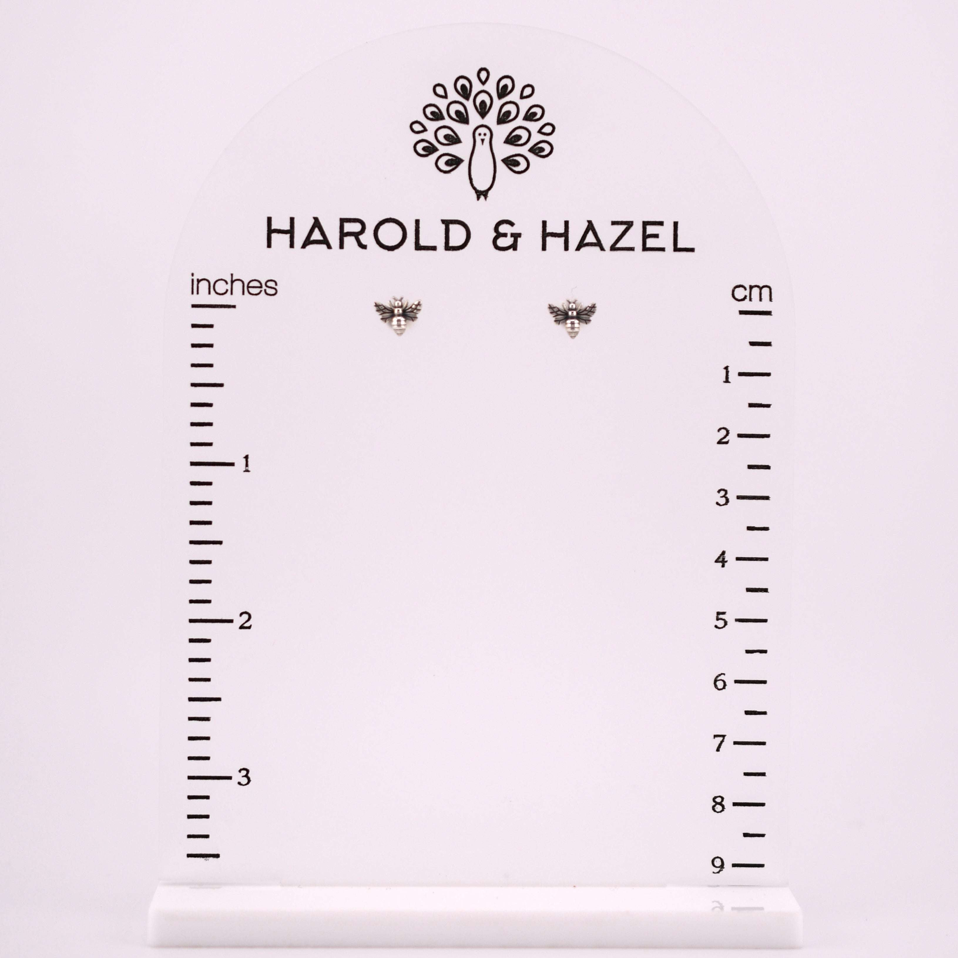 Tiny recycled sterling silver bee post earrings with detailed wings and body, displayed on a ruler.